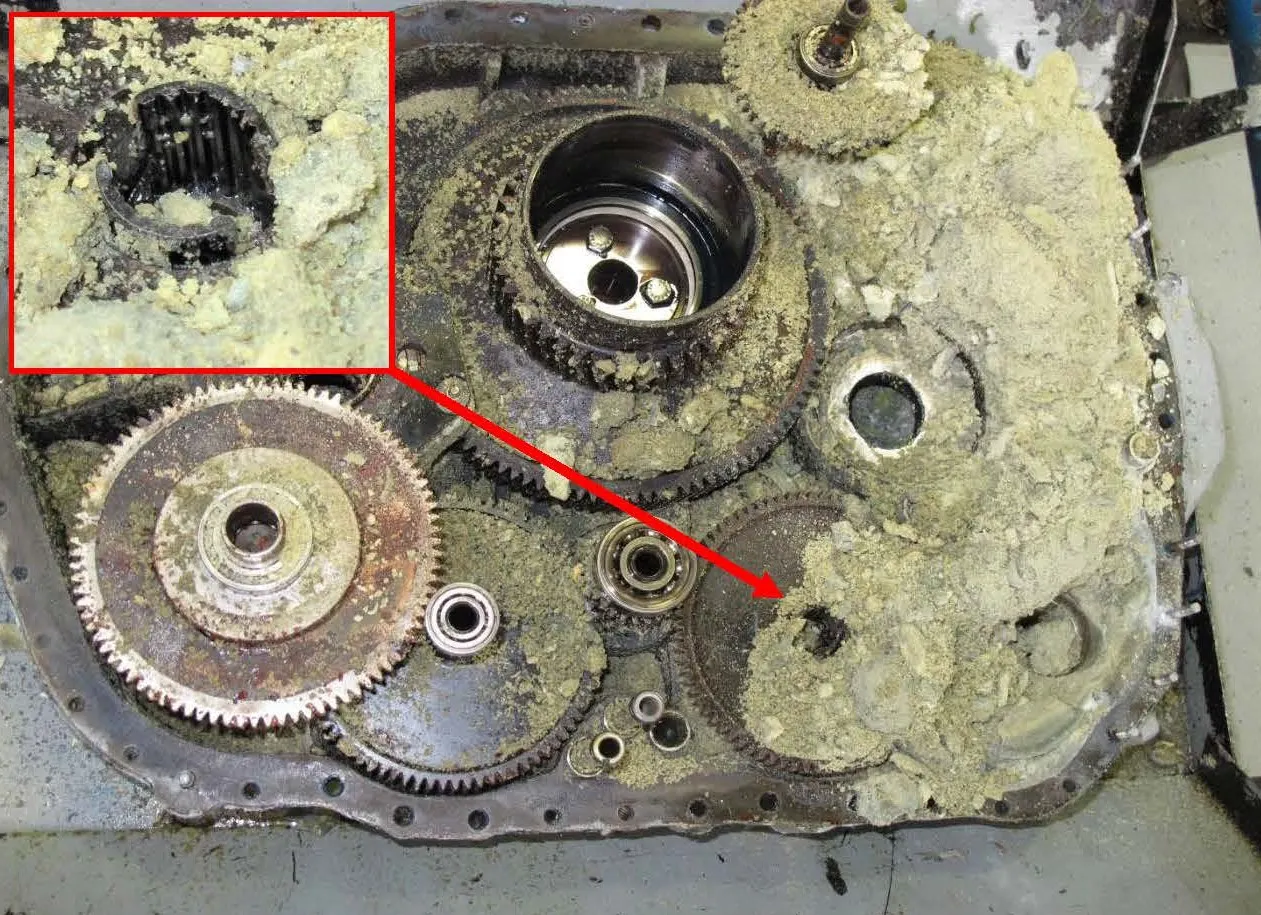 One half of the split opened accessory gearbox with a greenish powdery substance and a fractured drive shaft coupling to the oil pump gearshaft