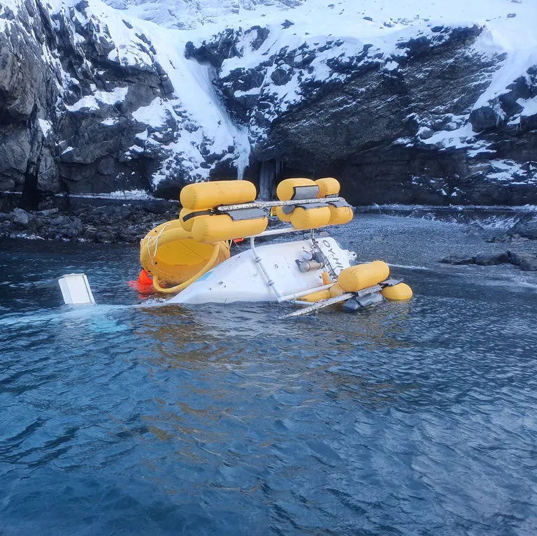 The helicopter on its LH side close to the shore