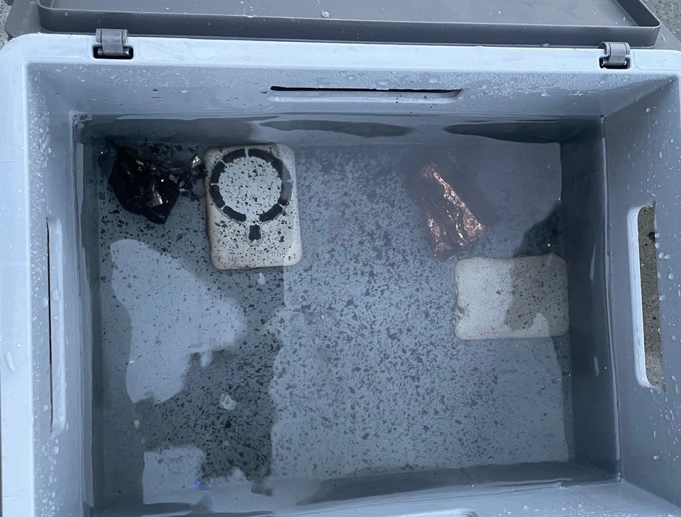 The power bank submerged in water in the waste bin.